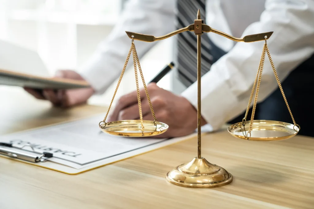 Balanza de la justicia y documentos sobre escritorio, representación de asesoría en Derecho Inmobiliario y Ley de Copropiedad.